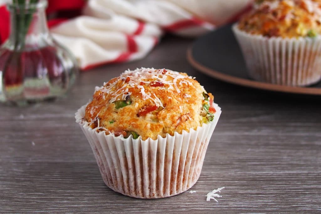 Muffin with bacon and spring onion in a basket sprinkled with cheese.