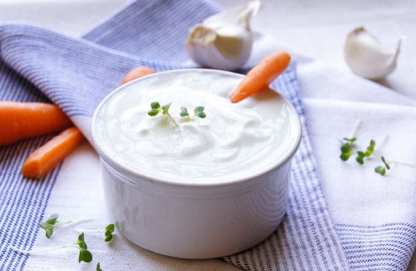 Joghurt-Mayonnaise-Sauce mit Knoblauch, serviert in einer Schüssel mit frischen Karotten.