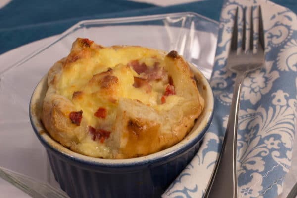 Cheese and ham pudding in a baking dish with a fork placed next to it.