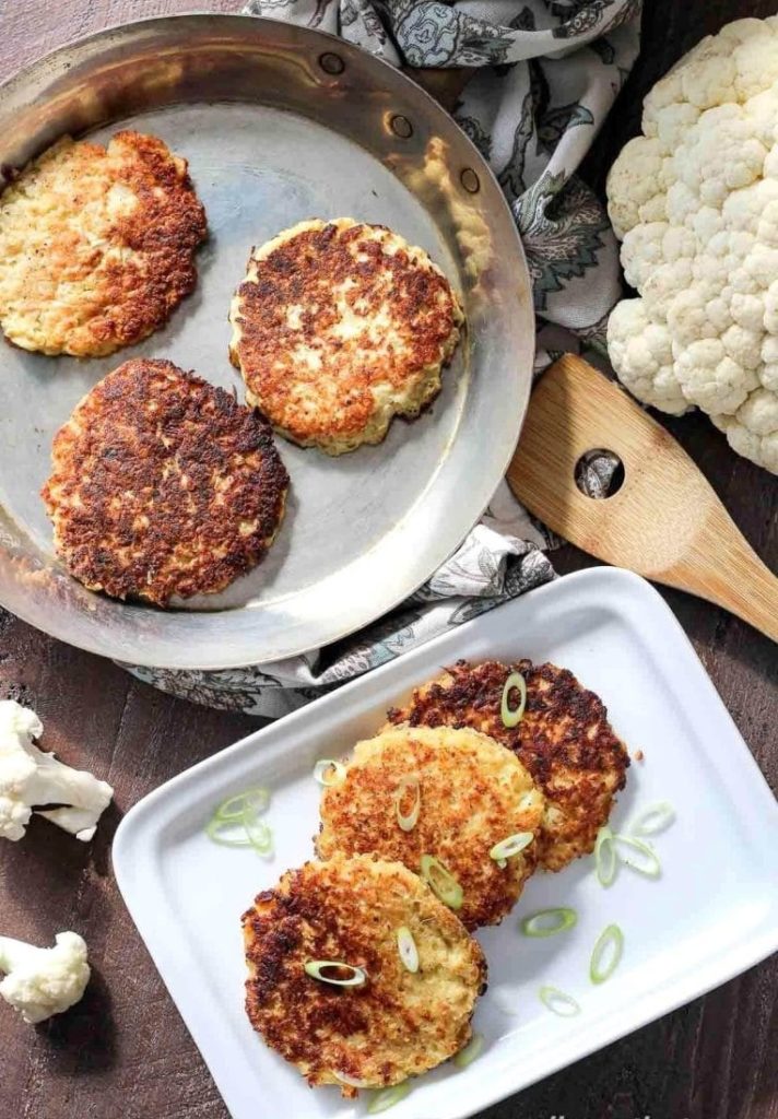 Cauliflower pancakes in a pan and on a plate.