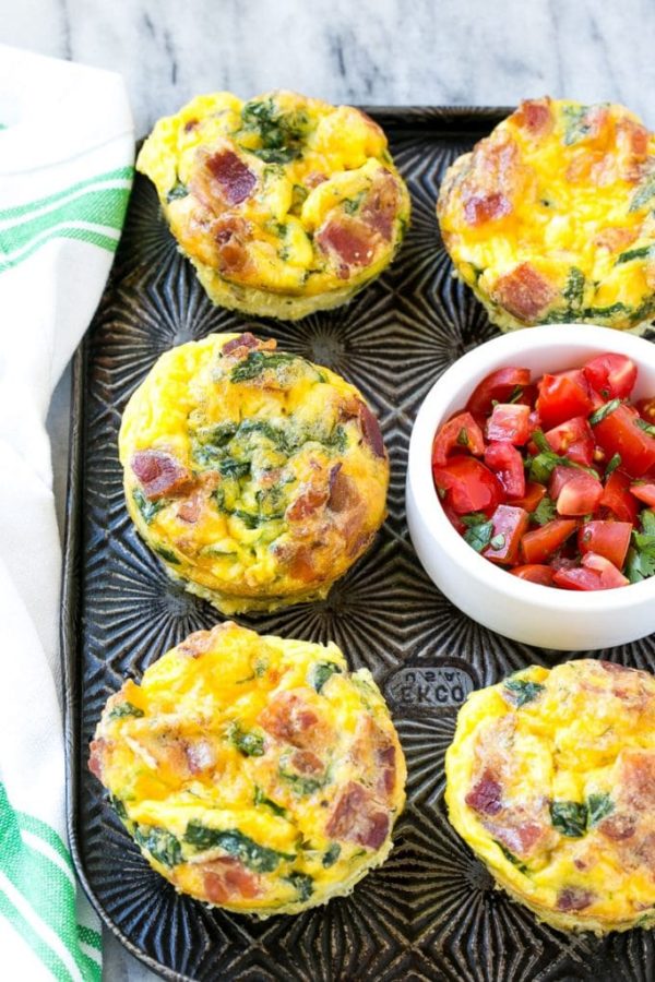 Bacon and vegetable muffins served on a tray with a bowl of fresh chopped tomatoes and herbs.