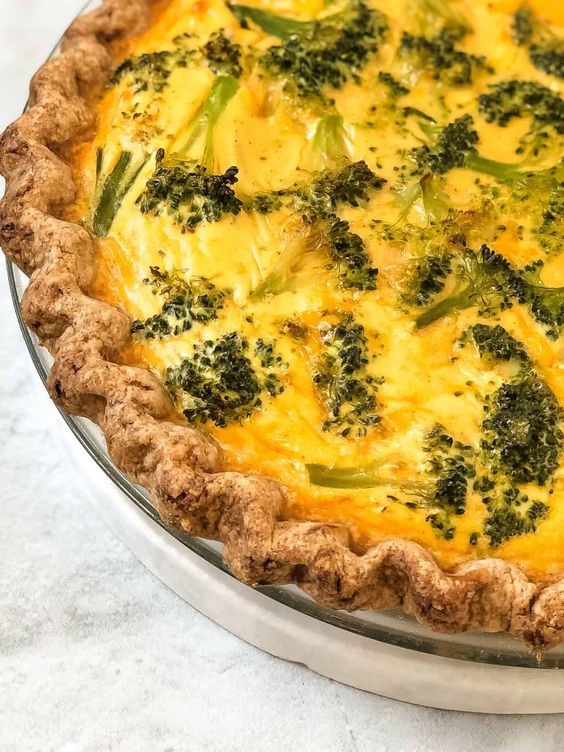 Pie with cheese and broccoli florets.