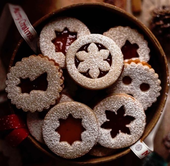 Linecké cukroví v misce posypané moučkovým cukrem s vánočními vykrojenými motivy