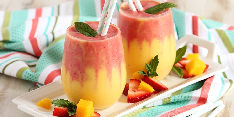 Zweifarbiger Mango-Erdbeer-Smoothie mit frischen Früchten und Minze.