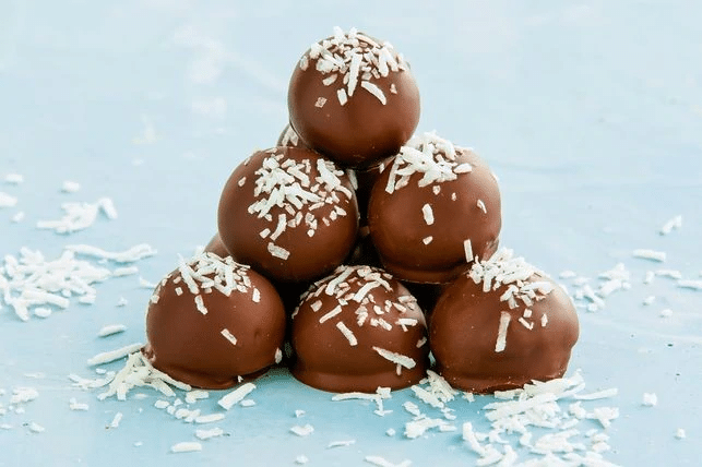 Traditional rum balls dipped in chocolate and sprinkled with coconut.