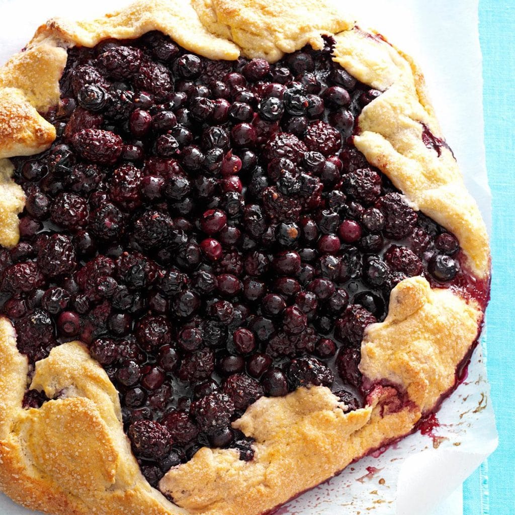 baked round cake covered with blueberries and blackberries