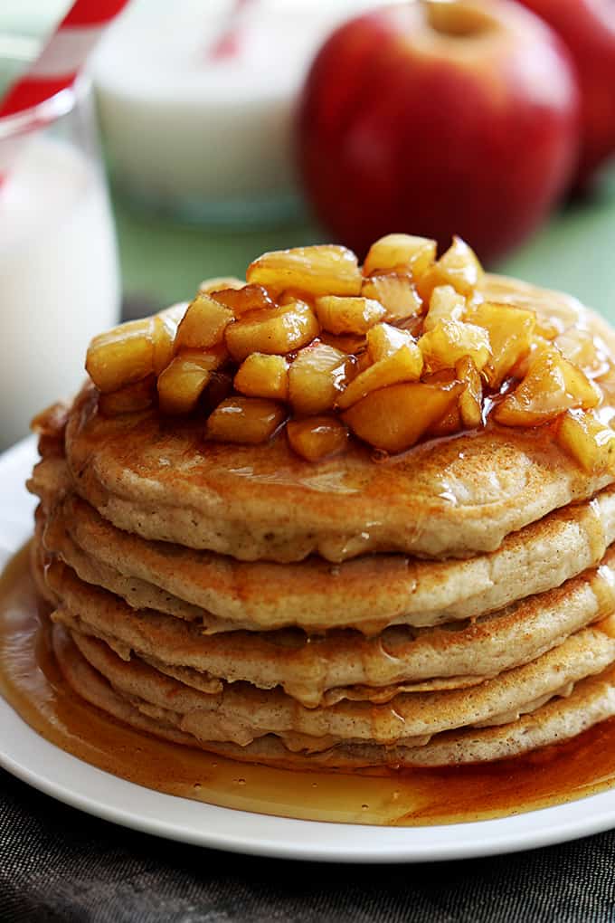 Yogurt fritters with apples, stacked on top of each other on a plate and covered in syrup.