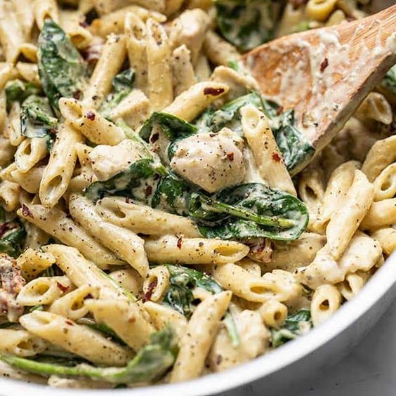Penne pasta with leafy spinach and cream sauce.