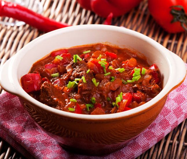 Goulash with pieces of peppers decorated with chives