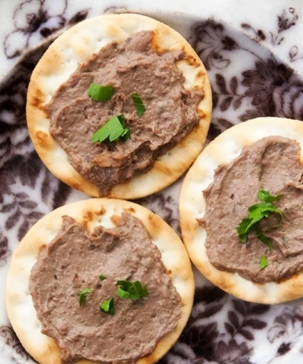 Homemade liver pâté, spread on crackers, garnished with parsley.