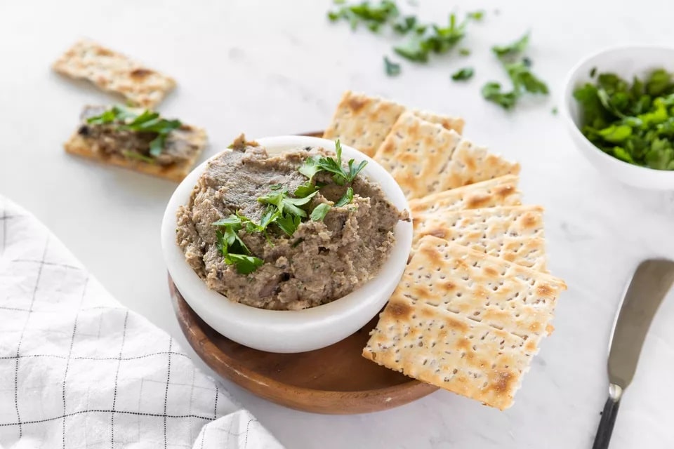 Mushroom pate spread in a bowl decorated with fresh herbs and served with crackers