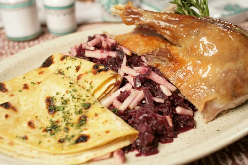 Goose with red cabbage and potato pancakes on a plate