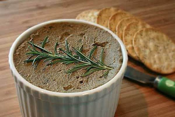 Duck meat spread decorated with a sprig of thyme in a small baking dish