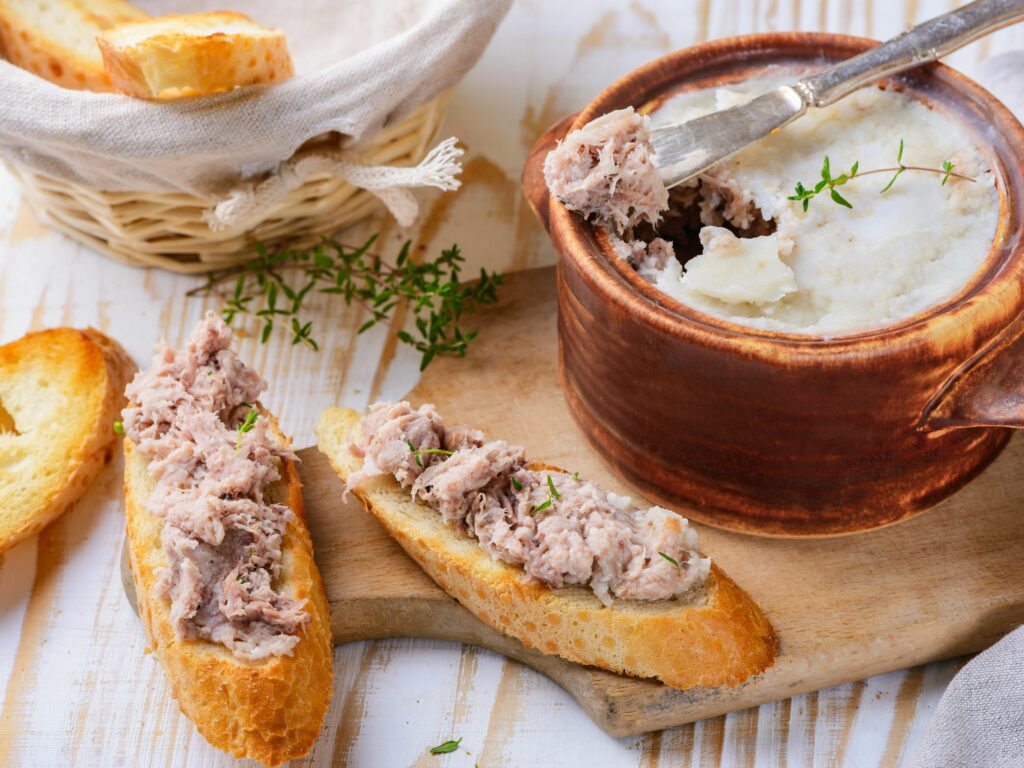 Homemade rillettes spread on a baguette and stored in a pot