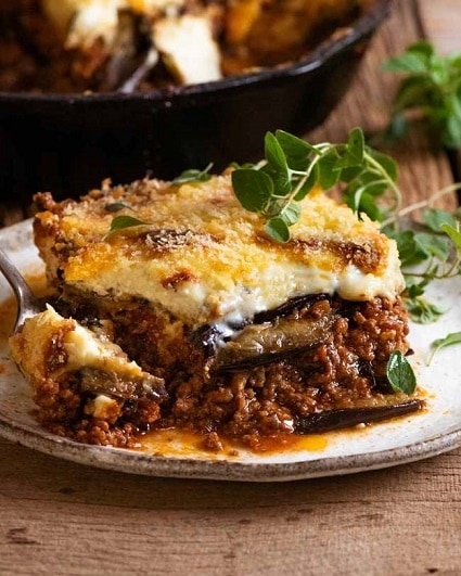 Juicy Greek moussaka with eggplant decorated with herbs.