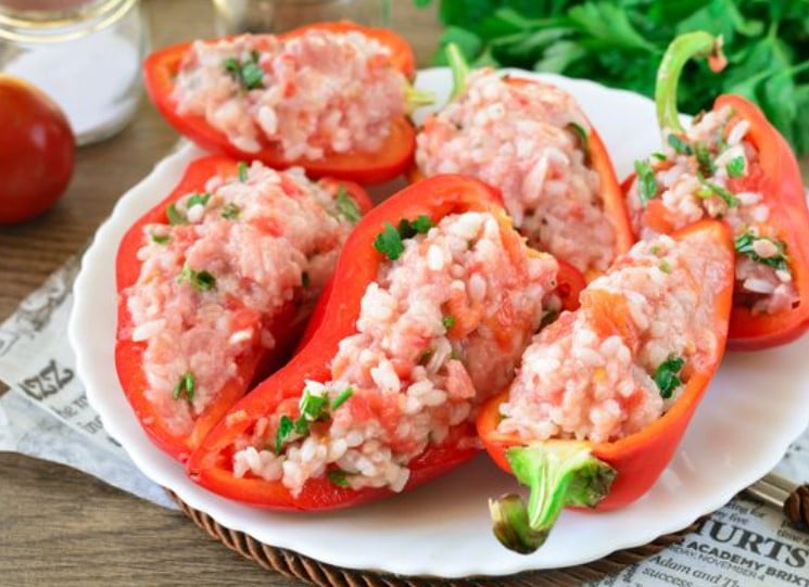 Raw red peppers stuffed with a mixture of ground meat and rice ready for baking