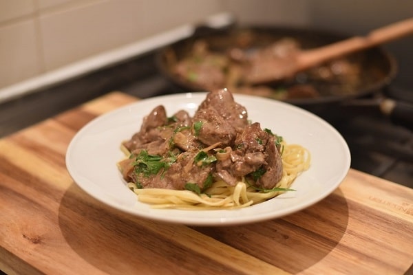 Fried liver with cream sauce and pasta, garnished with parsley.