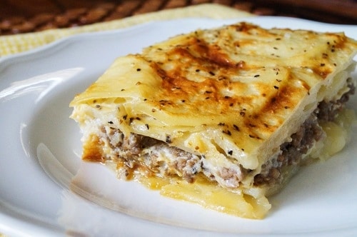Serbian moussaka with minced meat and baked eggplant, served on a white plate.