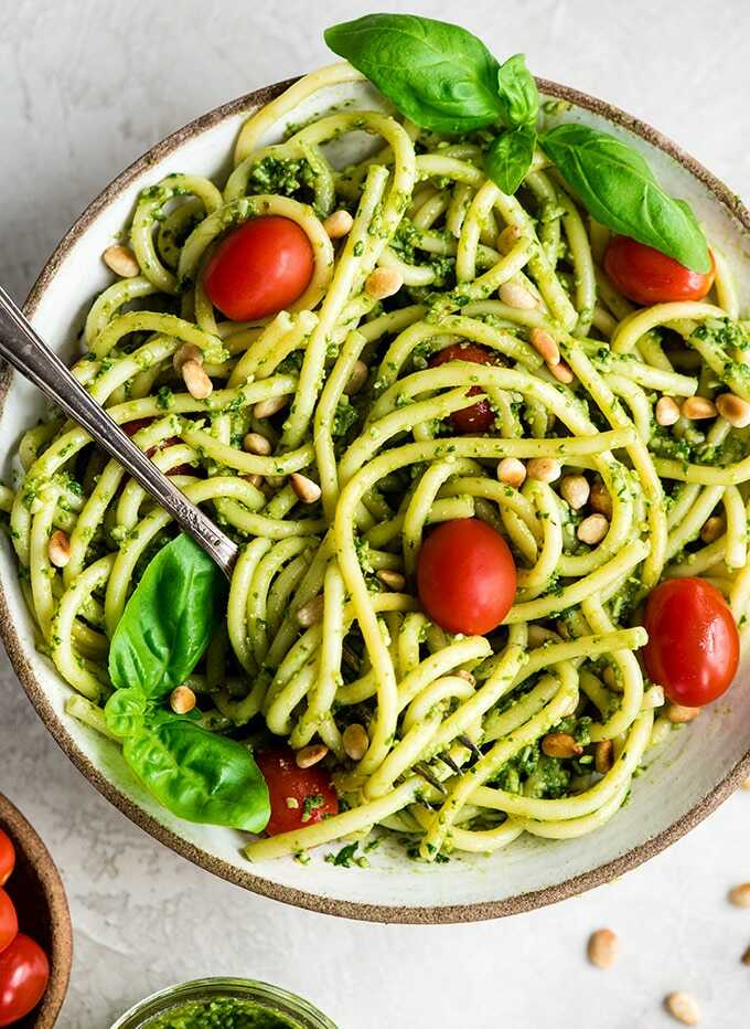 Spaghetti with pesto, cherry tomatoes and basil on a plate.