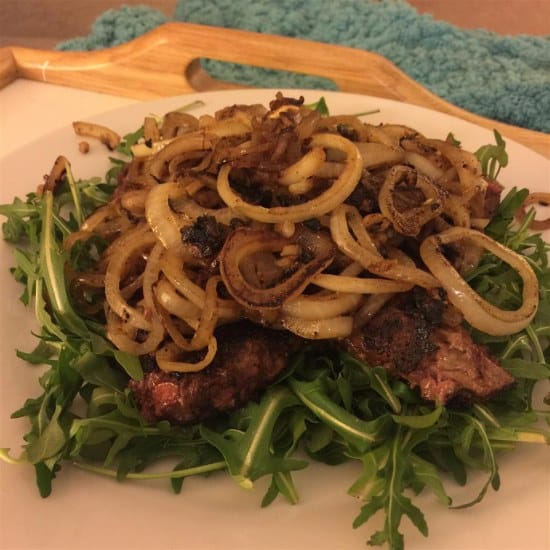 Roasted beef liver with onion served on rocket salad