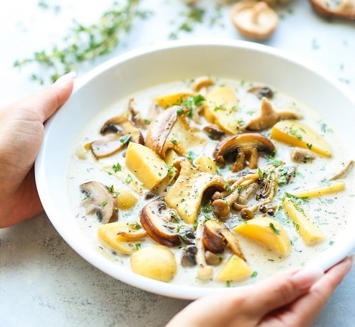 Potato soup with mushrooms, decorated with fresh herbs.