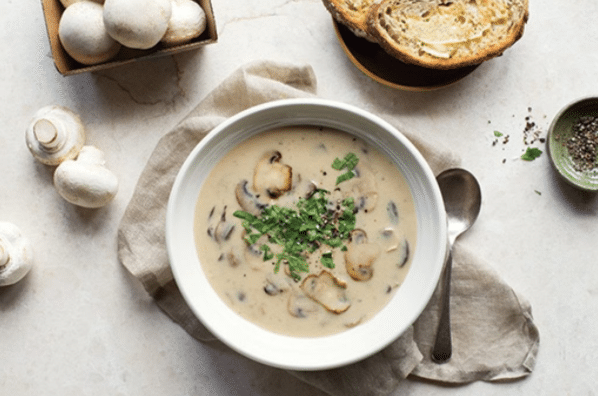 Bílá polévka z hub, zdobená čerstvými bylinkami. 