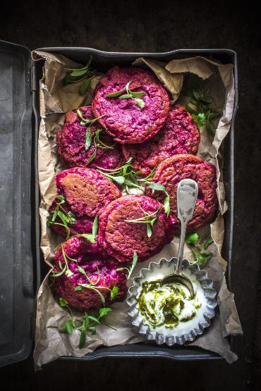 Beetroot pancakes with Greek yogurt and pesto in a bowl with a spoon.
