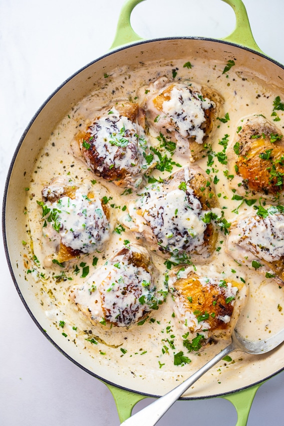 Chicken thighs with cheese sauce and parsley.