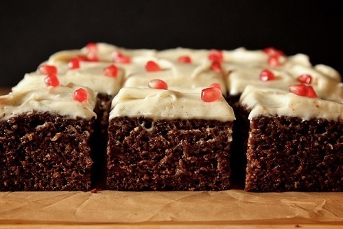 Gingerbread pieces with orange, decorated with cream frosting and pomegranate seeds.