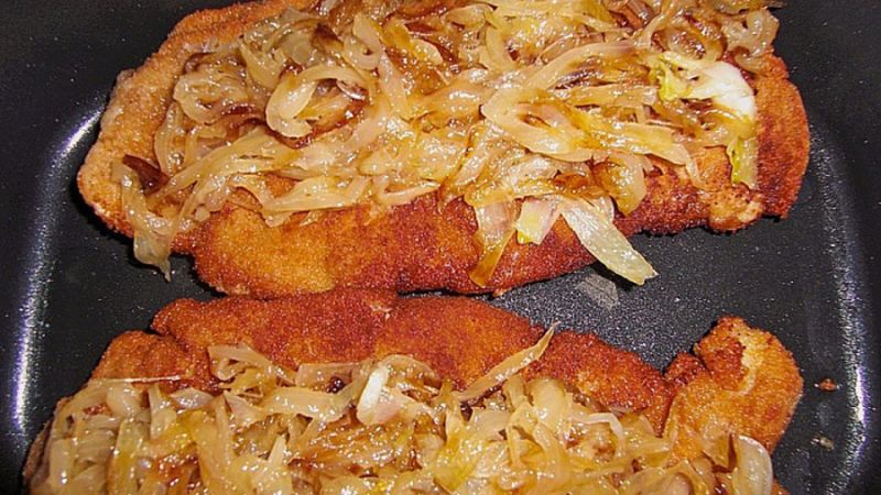 Pork chops coated in breadcrumbs and covered with fried onions