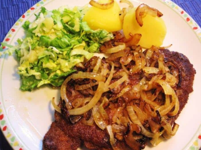 Obrácené řízky servírované s cibulkou, bramborem a salátkem