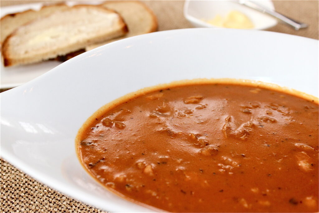 Tradiční polévka s dršťkama,  paprikou, majoránkou a chlebem v bíém talíři. 