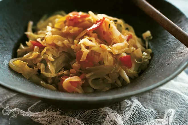 White cabbage with carrots, chili and bacon in a pan.