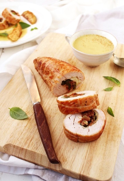 Sliced turkey roulade, stuffed with sun-dried tomatoes and mozzarella, garnished with fresh herbs and served with applesauce.