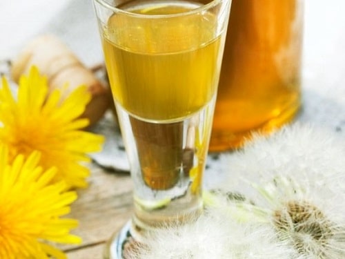 Golden dandelion liqueur in a glass.