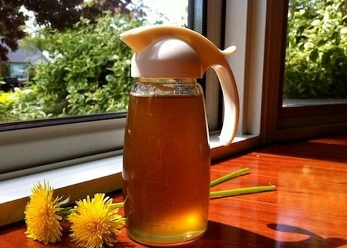 Dandelion syrup in a glass with a dispenser.