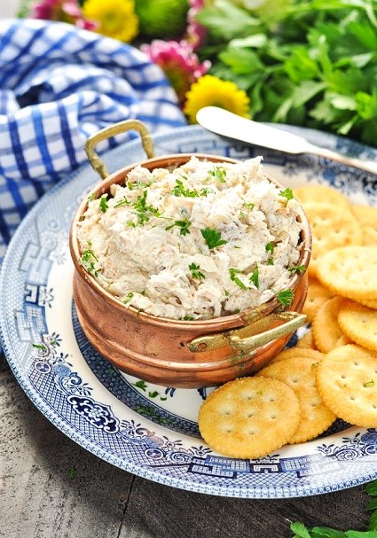 White spread with fresh herbs, served with round biscuits.