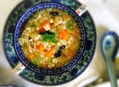 Suppe mit Gemüse und Wakame-Algen in einer blauen Schüssel.