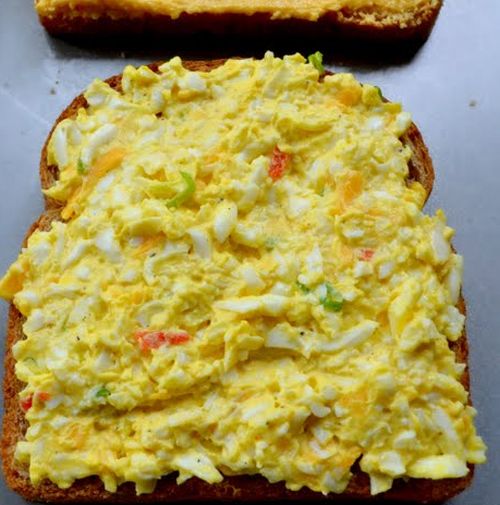 A slice of whole wheat bread spread with egg and cheese spread