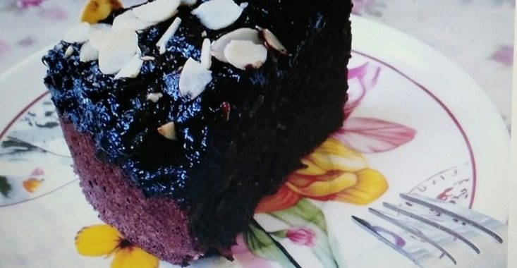 Kakaový dort posypaný mandlemi servírovaný na talíři.