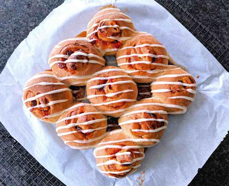 Buns with plums decorated with icing on paper.