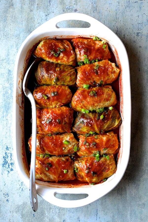 Cabbage rolls filled with minced meat and vegetables in a baking dish with a fork.