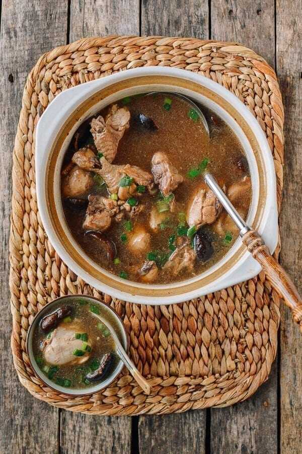 Chicken and mushroom soup in a large bowl with a ladle on a wicker tray.