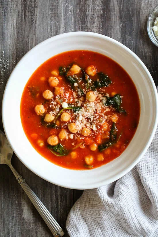 Chickpea and tomato soup sprinkled with parmesan, served on a plate.