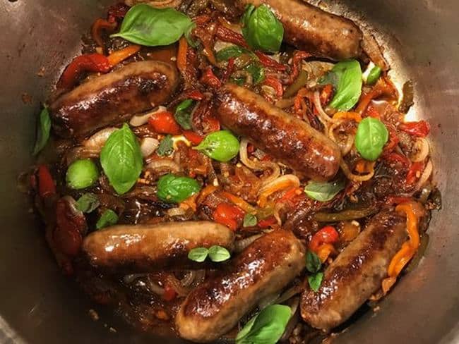 A mixture of Italian sausages, peppers, onions and basil leaves