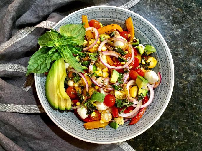 Salad with avocado, peppers, tomatoes, onions and mozzarella on a plate.