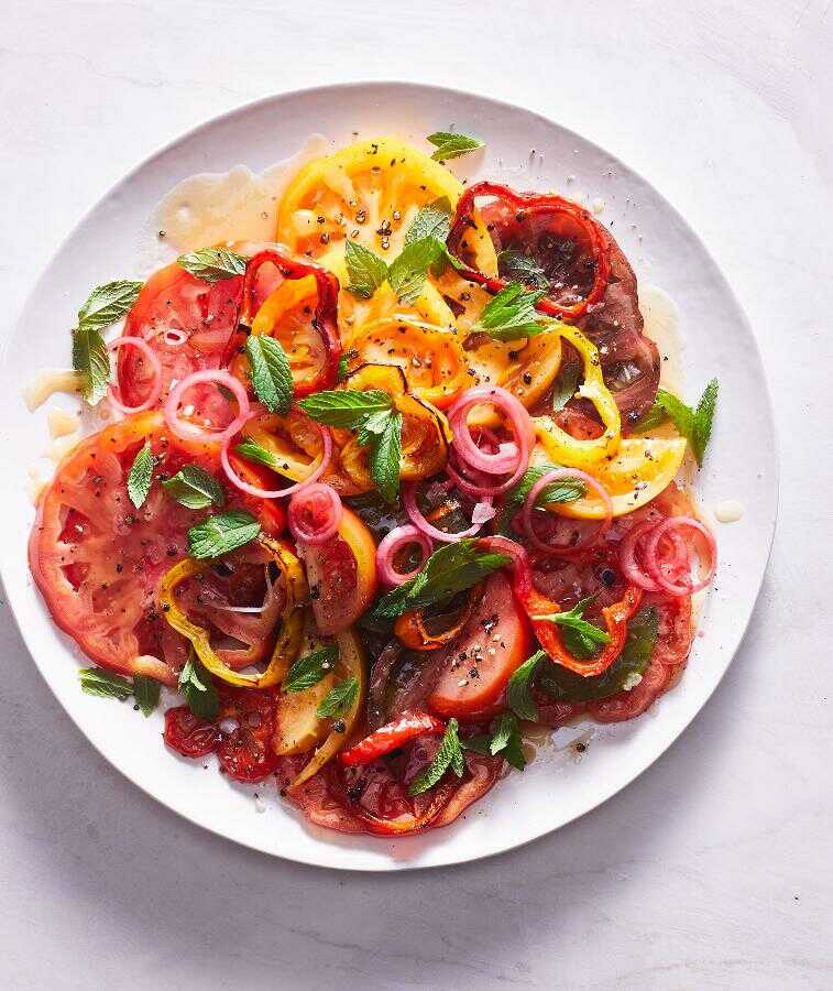 Salát z rajčat, paprik, cibule a máty servírovaný na talíři.