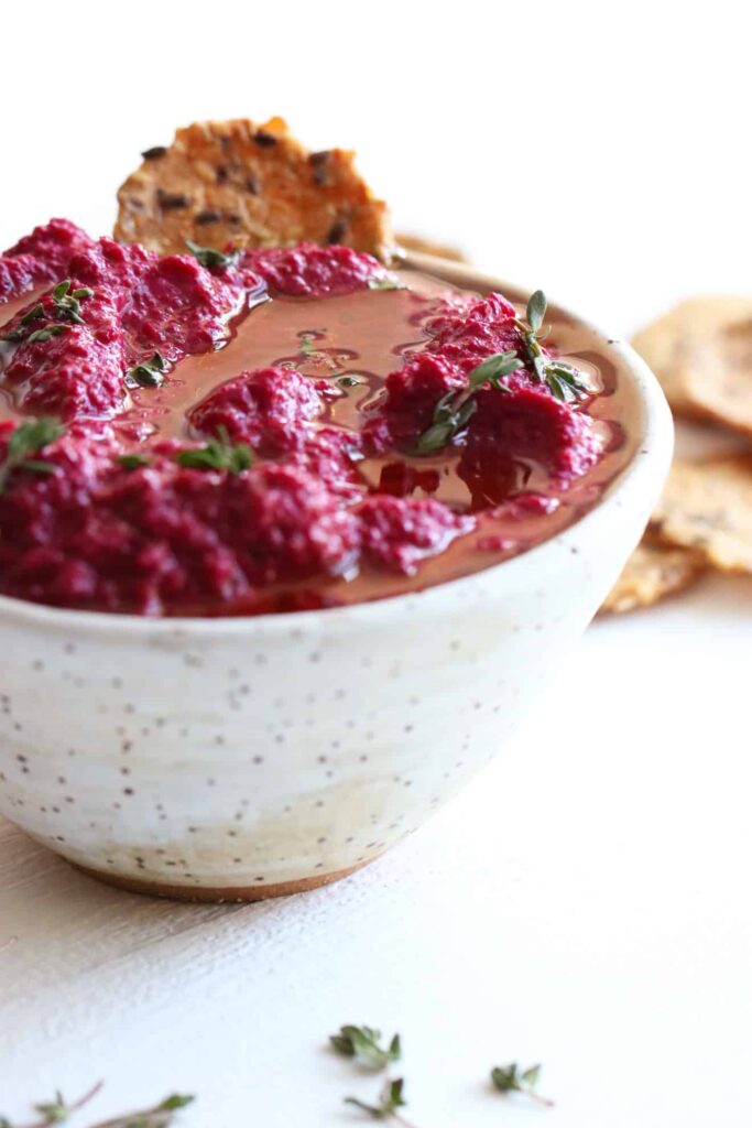 Beet spread with horseradish served in a bowl and sprinkled with herbs.