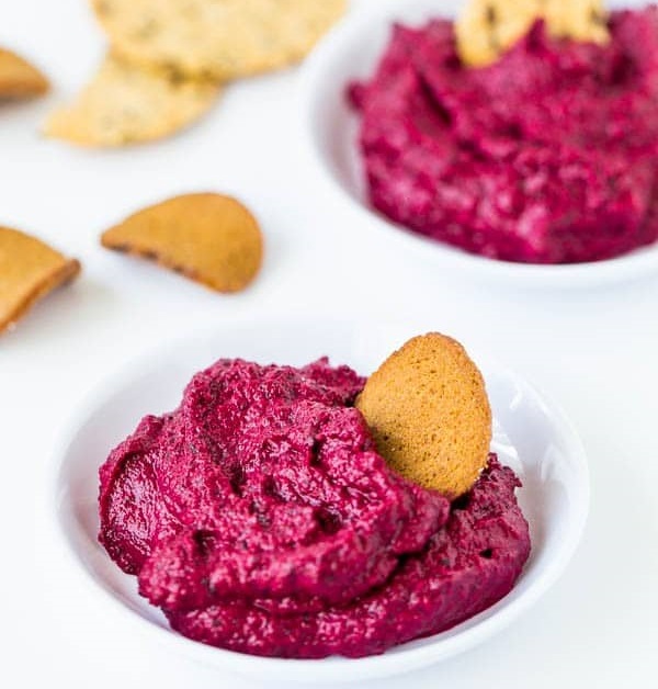 Baked beetroot dip in a bowl with a cracker.