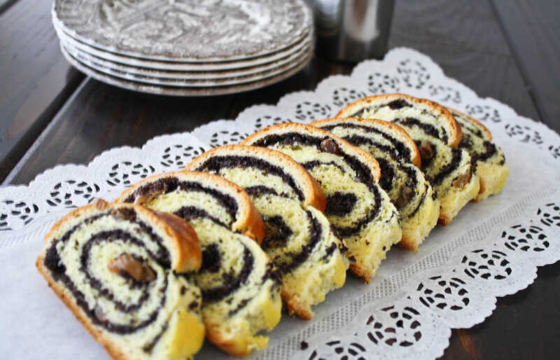 A strudel filled with poppy seeds cut and served on a tablecloth.